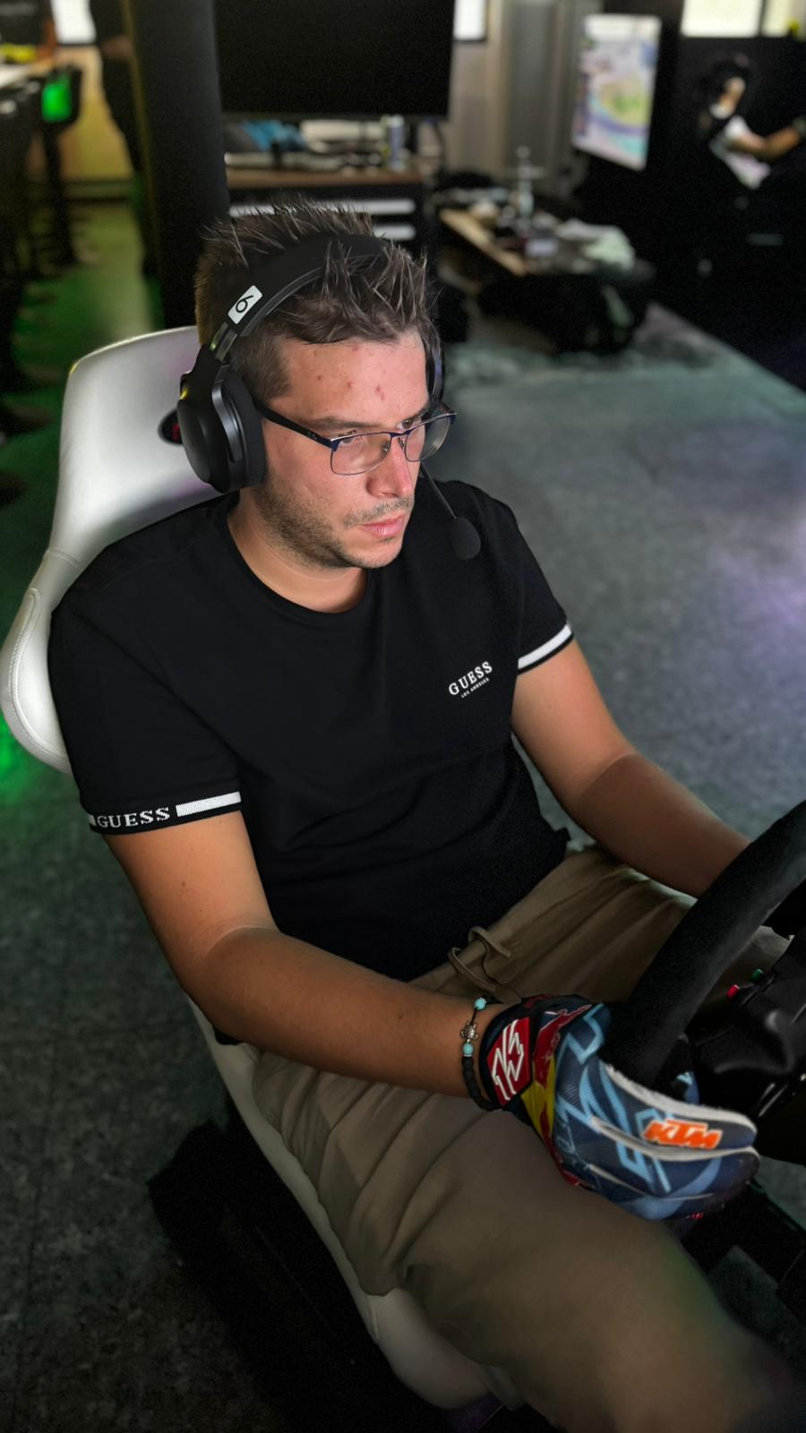Pilota in sessione sim racing con cuffie e volante a RaceRepublic Morbio Inferiore